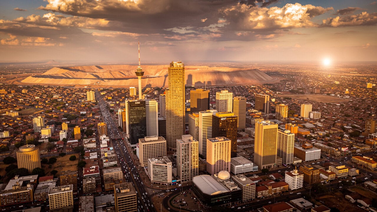 Aerial view of Johannesburg skyline at sunset, showcasing modern buildings and urban landscape.